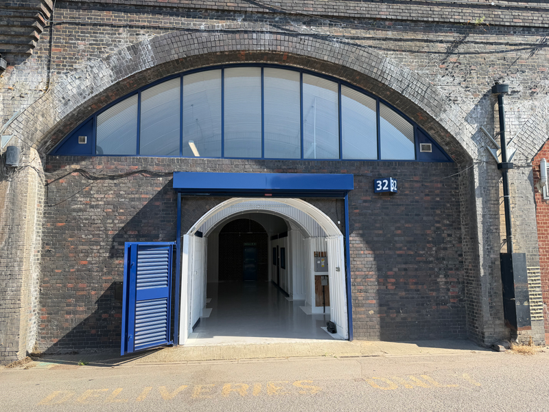 The front of an arch, with high level glazing, an open electric roller shutter entrance big enough for vehicle access, and a pedestrian door.