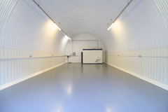 An empty arch with white lining and a WC cubicle to the back.