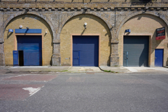 The front of an arch with a closed electric roller shutter entrance big enough for vehicle access. 