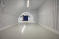 An empty arch with lining, facing the front electric roller shutter entrance, which is closed.