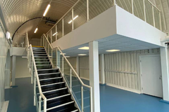 An arch with lining and a ground floor level and a mezzanine level, connected by stairs.