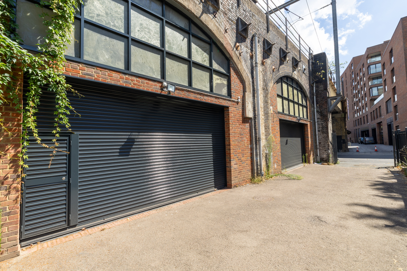 The front of an arch, with high level glazing, a closed electric roller shutter entrance big enough for vehicle access, and a pedestrian door.