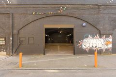 The front of an arch with an open electric roller shutter entrance big enough for vehicle access.