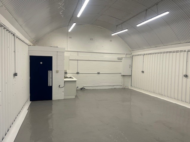 An empty arch with white lining and a WC cubicle to the back.
