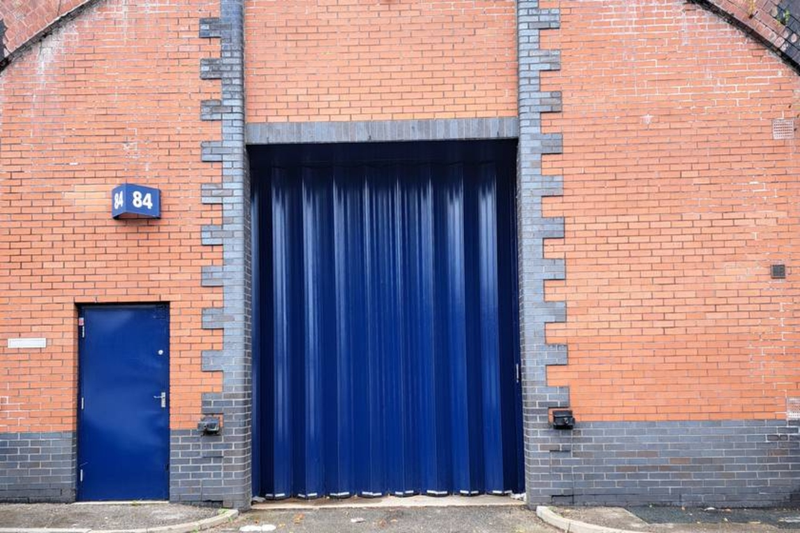 The front of an arch with a closed metal concertina door that can be pulled back fully. 