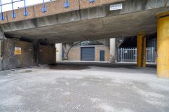 The front of an arch, which has a front yard and sits behind metal fencing. The arch has a closed electric roller shutter entrance large enough for vehicle access.