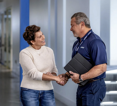 ArcBest employee shaking hands with female customer in a hallway.