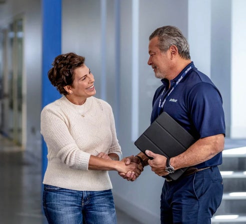 ArcBest employee shaking hands with female customer in a hallway.