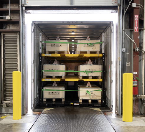 Vaux Freight Movement System showing un-stackable server equipment secured on racks inside a shipping container at a warehouse dock.