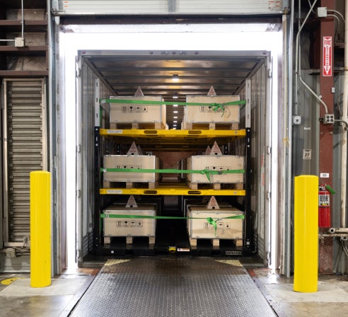 Vaux Freight Movement System showing un-stackable server equipment secured on racks inside a shipping container at a warehouse dock.