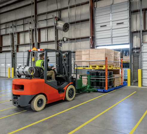 Forklift operator using Vaux to move vertically stacked pallets inside a warehouse.