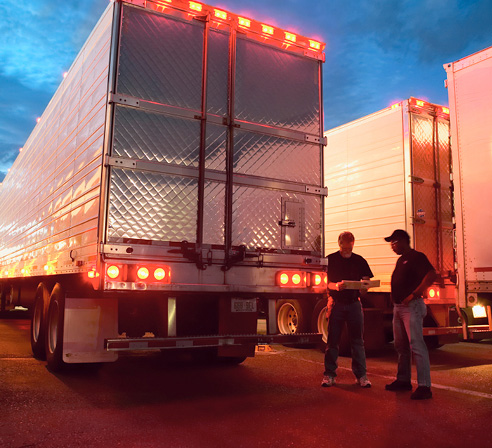Two drivers standing outside their truck discussing their plan.