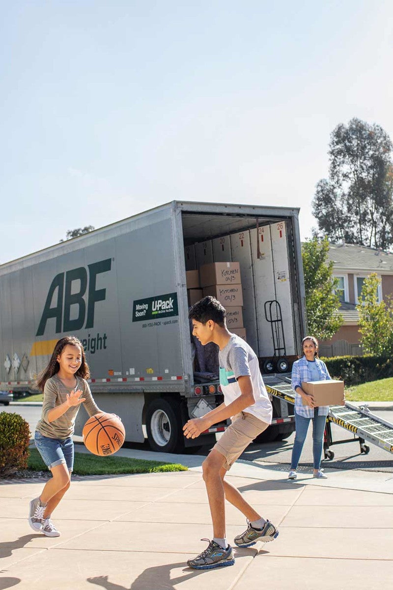 children playing basketball while parent carries box to ABF trailer