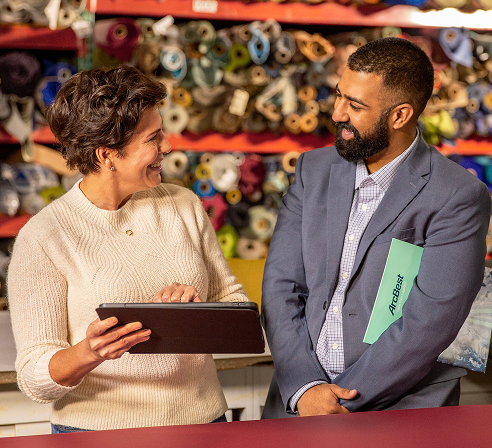 Man and woman discussing small business shipment data on a tablet.