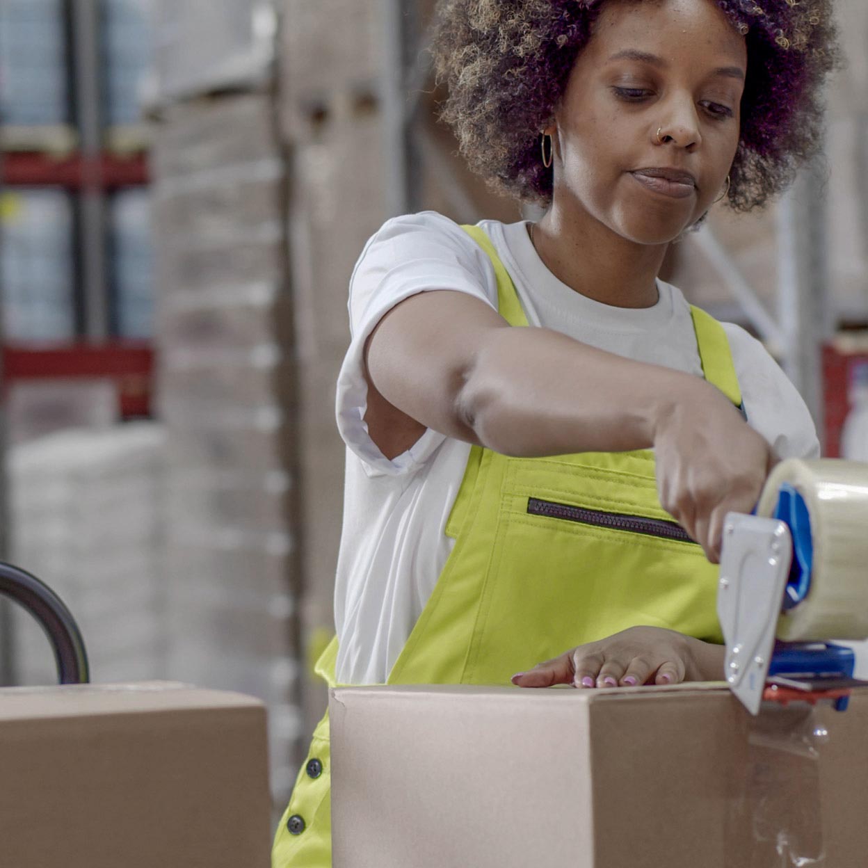 Woman taping a box shut before putting it on a pallet.