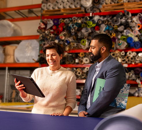 A woman shows an ArcBest representative information on a tablet in a warehouse.