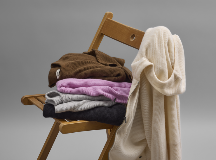 Vuori cashmere sweaters folded and hanging on a chair