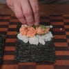 hand assembling salmon and avocado hand rolls