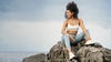 woman sitting on rocks wearing halo essential bra and performance jogger
