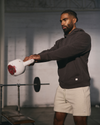 man wearing vuori swinging kettlebell inside a gym