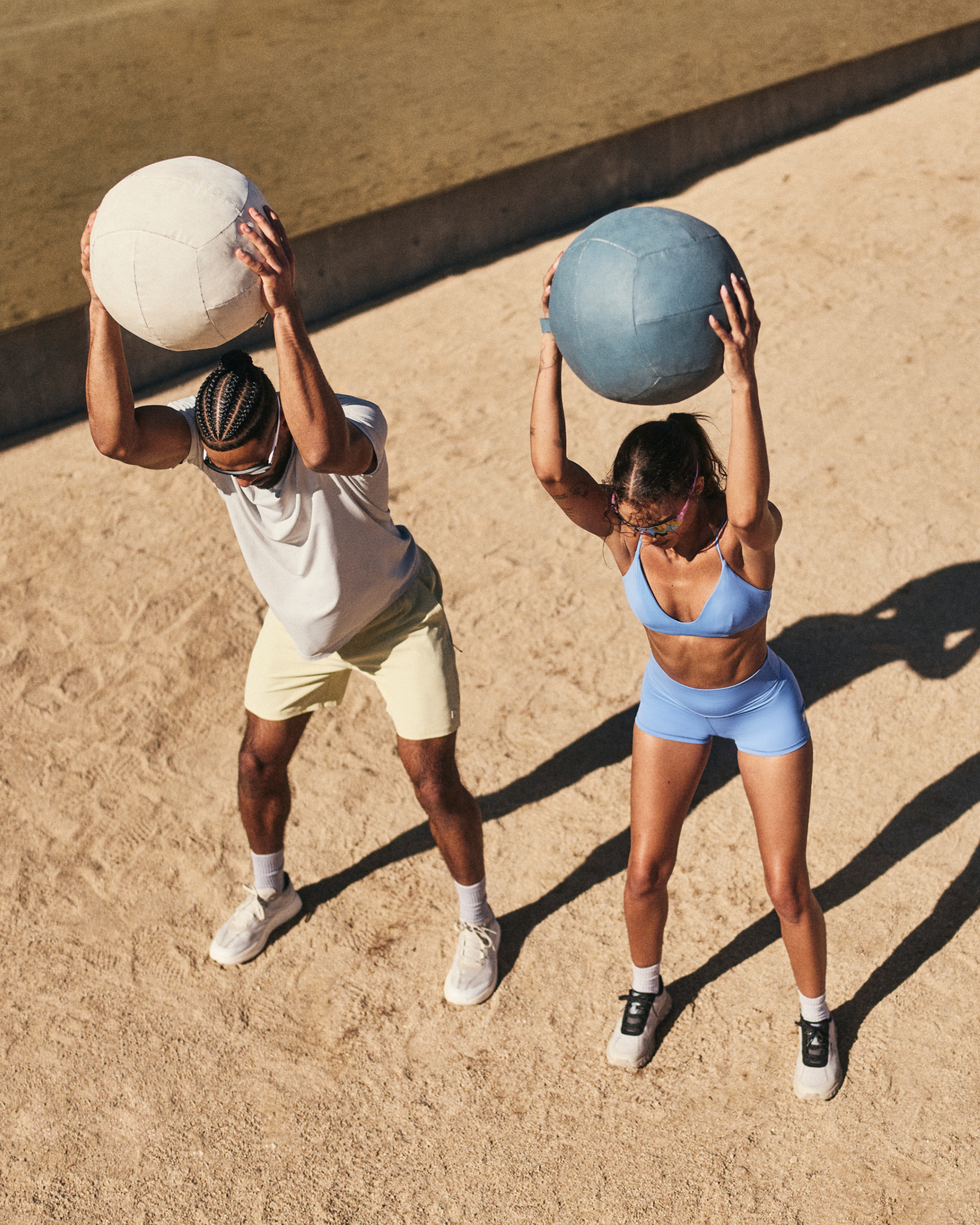 man and woman wearing vuori throwing medicine balls 
