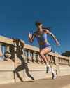 woman wearing vuori running on bridge