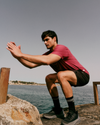 man wearing vuori doing squats by the ocean