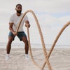 man swinging ropes wearing vuori strato tech tee