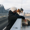 one man and two women looking over bridge at a lofoten fjord