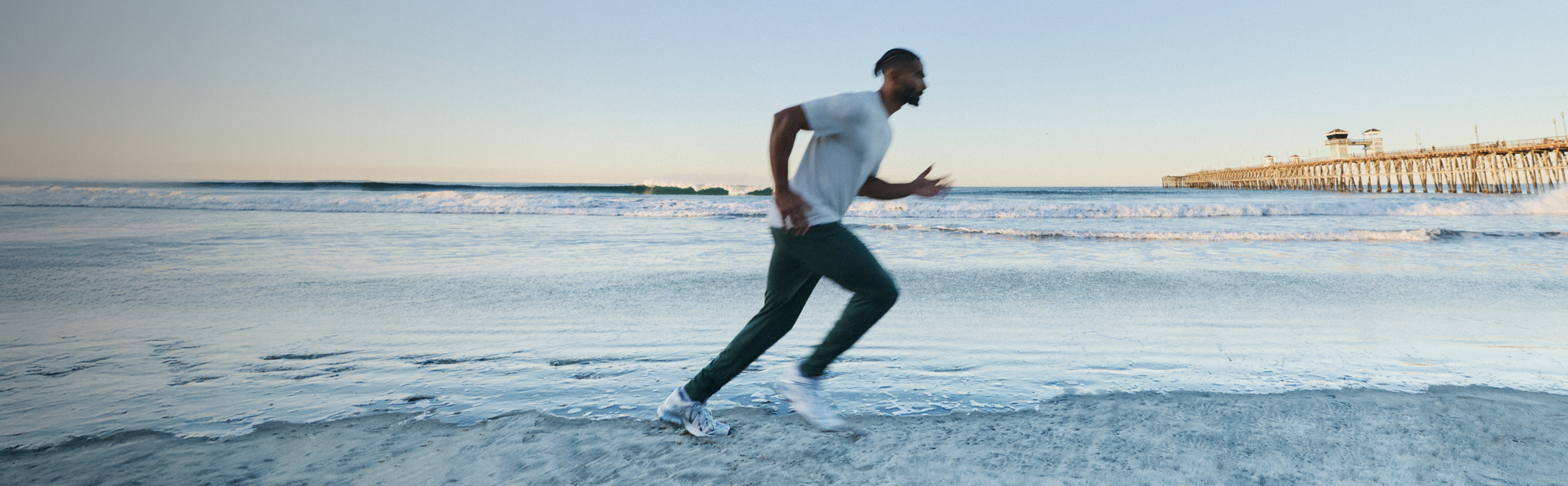 man running on the beach wearing sunday performance jogger and strato tech tee