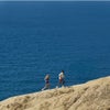 man and woman running up ocean bluff