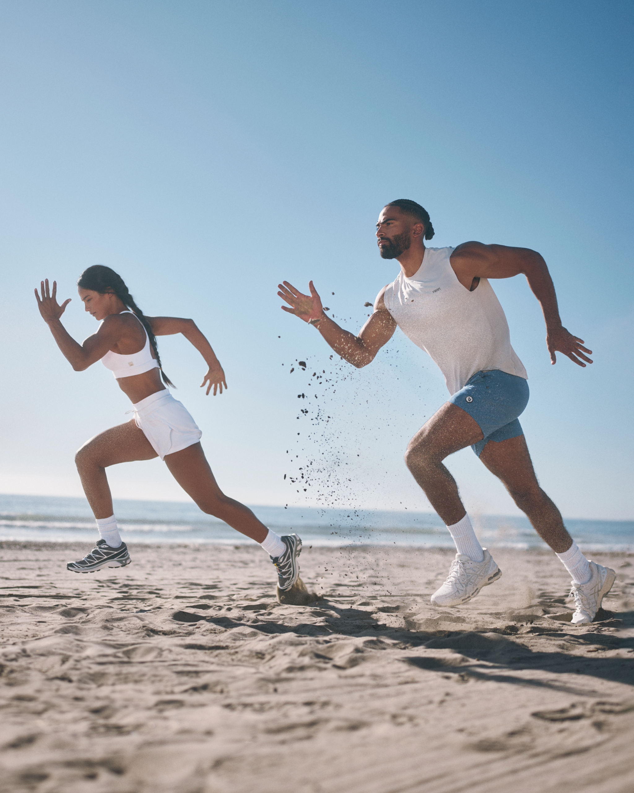 man and woman wearing vuori running on the beach