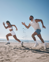 man and woman wearing vuori running on the beach