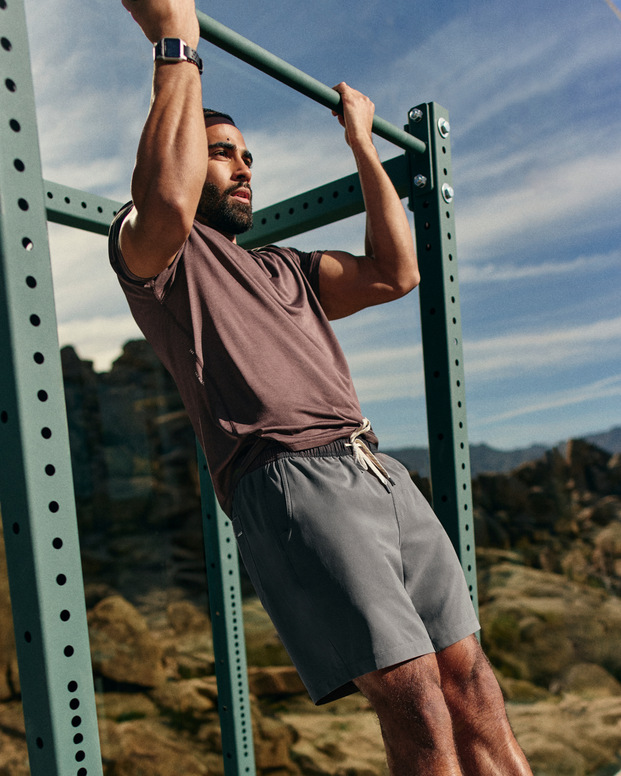 man wearing vuori doing pull ups in the desert
