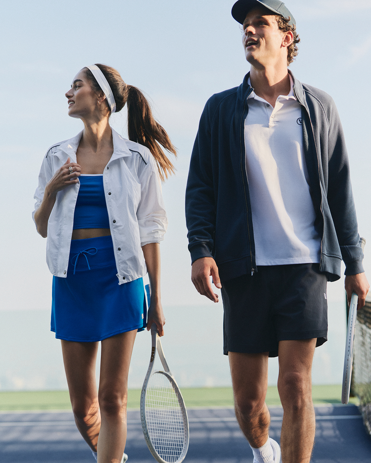 man and woman wearing vuori clothing on a tennis court
