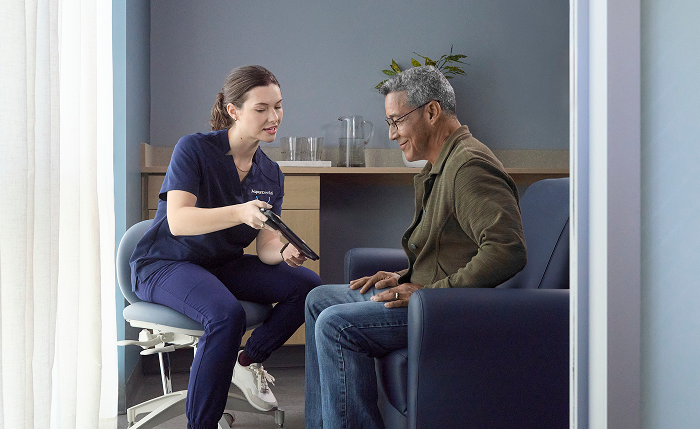 An Aspen Dental team member reviewing dental filling costs on a tablet with a senior male patient.