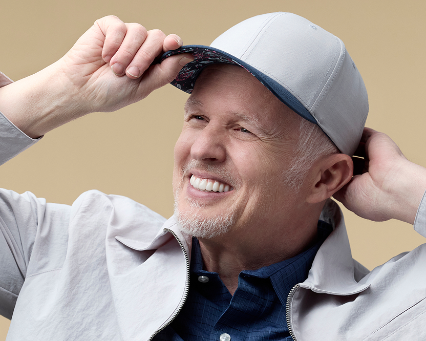 Smiling man wearing a baseball cap showing his custom-shaded Endura dental implants