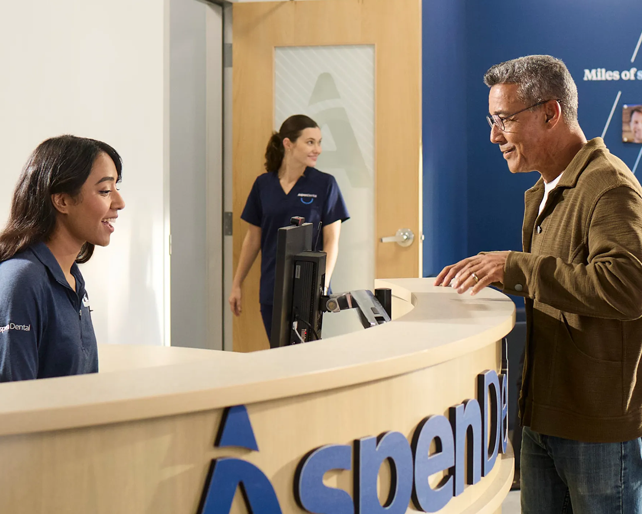 Patient checking in at the reception desk of an Aspen Dental office.