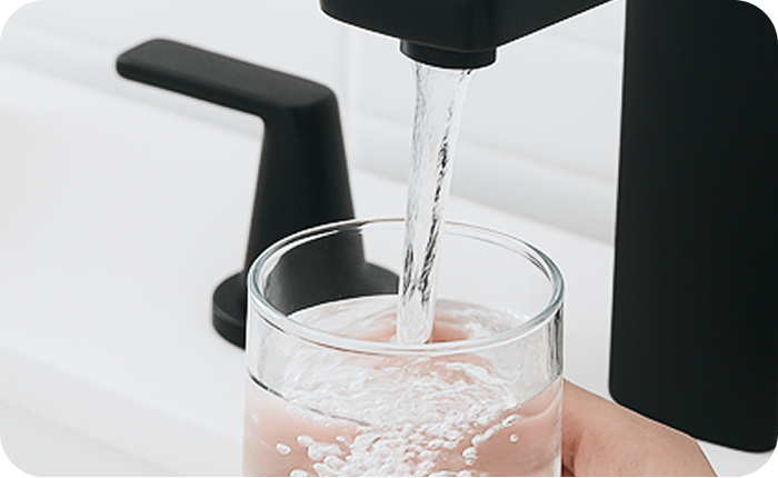 Water filling a glass from a faucet.