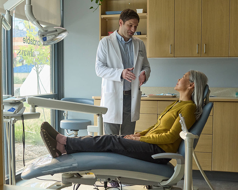 Dentist speaking with a patient seated in a dental chair during a visit at Aspen Dental.