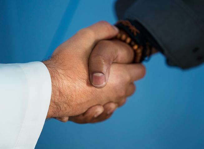 Two hands grabbing each other in a handshake, set against a blue background