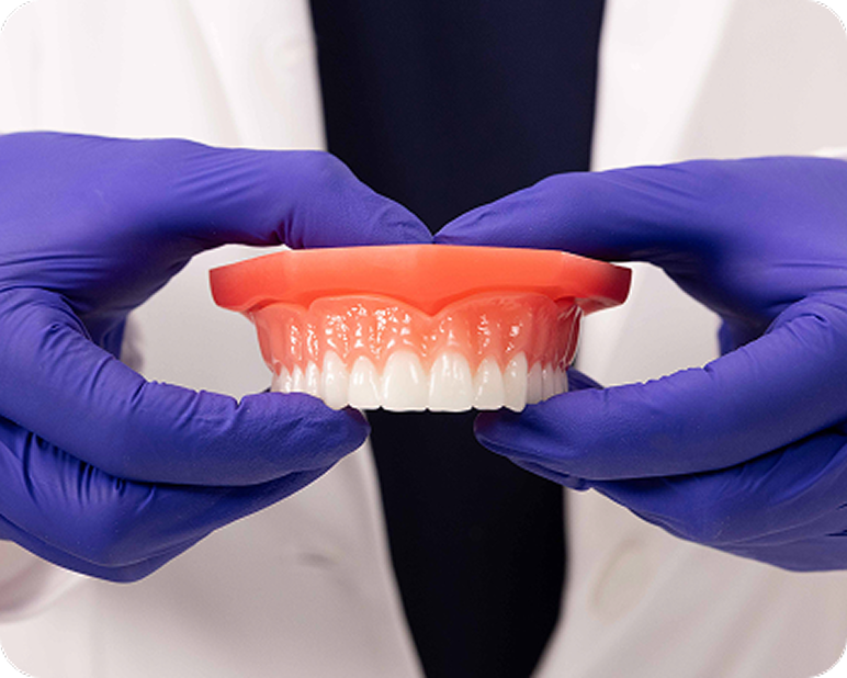 Dental professional holding a denture with both hands.