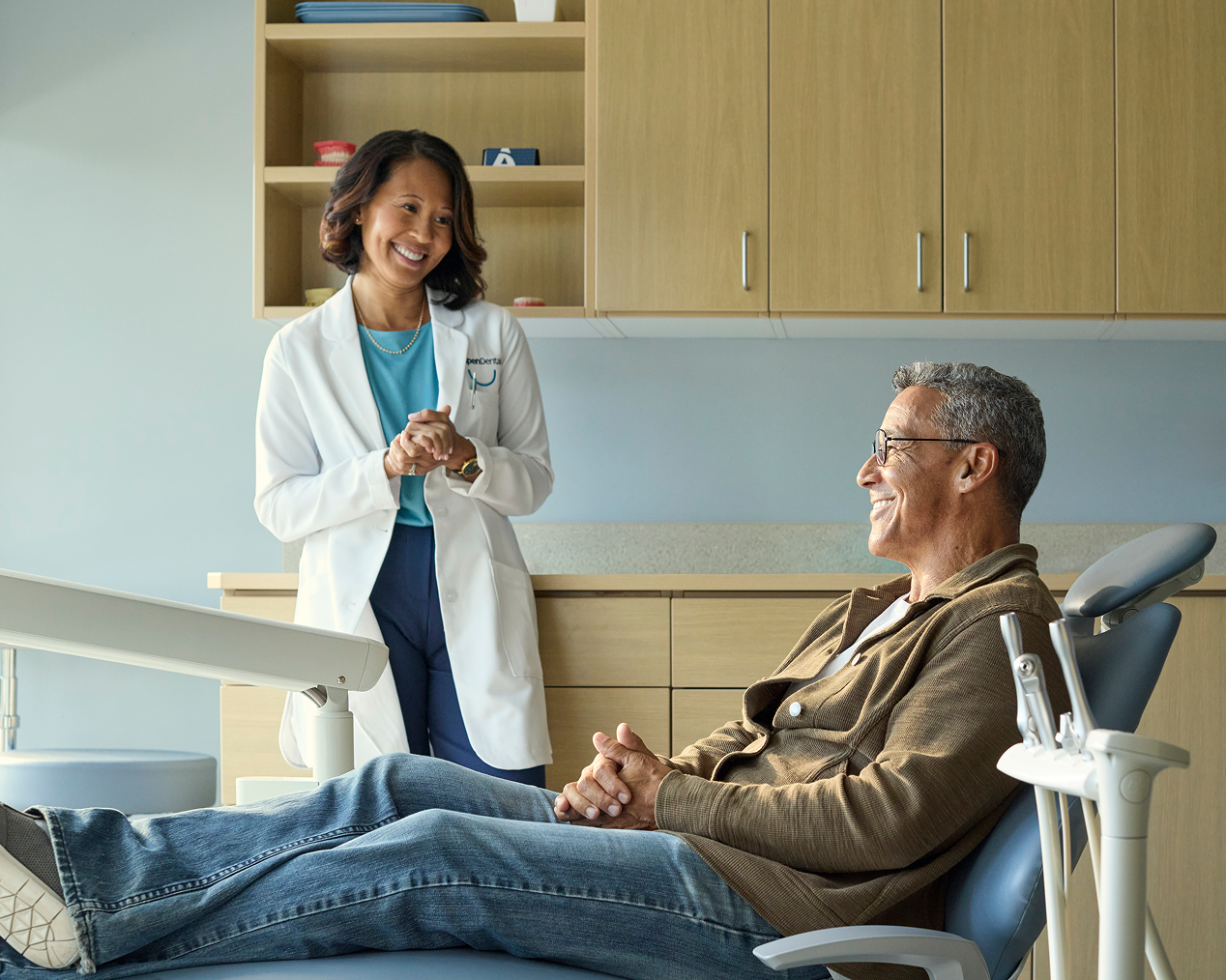 Alt text:
Aspen Dental professional speaking with an older adult man seated comfortably in a dental chair during a visit.