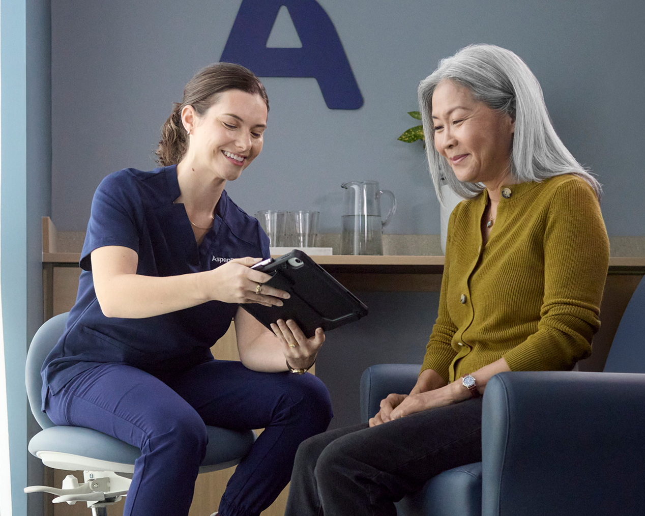 Alt text:
Aspen Dental team member reviewing information on a tablet with an older adult woman during a visit.