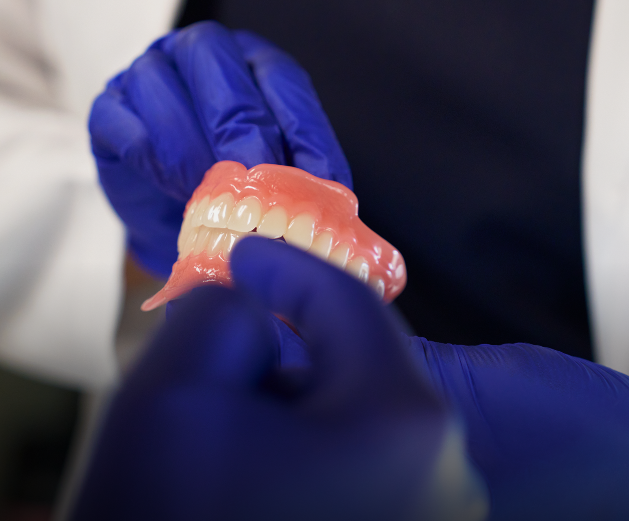 Gloved hands holding dentures