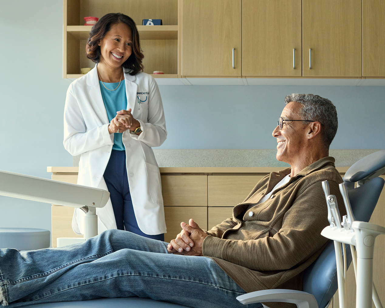 A dental professional smiles at a patient sitting in a dental office chair
