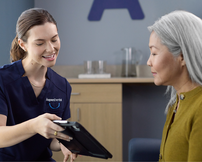An Aspen Dental care team member discussing treatment plan details with a patient seated in a treatment room.