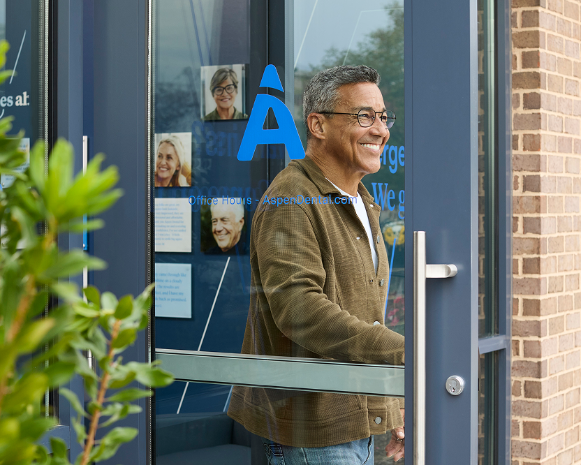 An older man smiles while exiting an Aspen Dental office