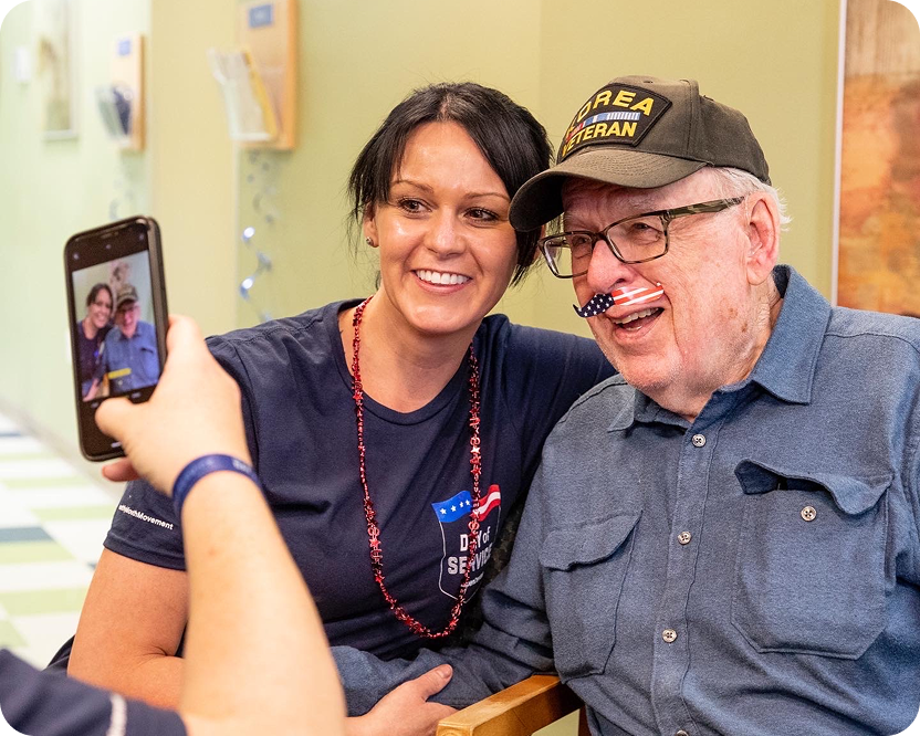 A woman takes a selfie with a smiling veteran