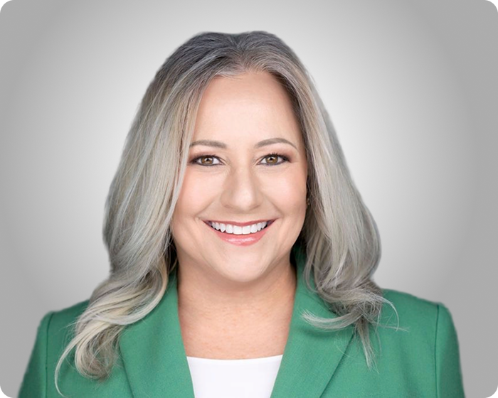 Professional headshot of a smiling woman in a green blazer